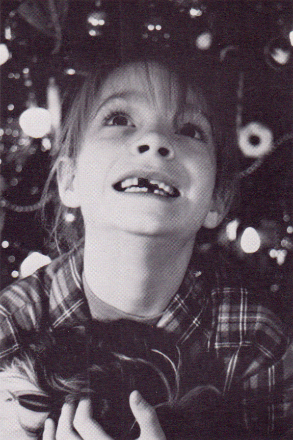 Photo of girl with missing teeth in front of Christmas tree